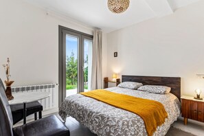 A bedroom with a bed, a table, a chair, a nightstand, and a view of the outdoors. - Apartment 'Tierra' with Sea Views, Private Terrace and Wi-Fi (La Vega)