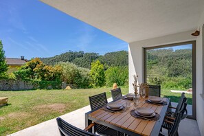 An outdoor dining area with a table set for four, surrounded by chairs, with a view of a forested hillside. - Apartment 'Tierra' with Sea Views, Private Terrace and Wi-Fi (La Vega)