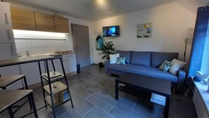 A modern living area with a sofa, coffee table, and a TV mounted on the wall. - Vacation apartment WESER im Relax - Belum near Otterndorf LK Cuxhaven (Belum)