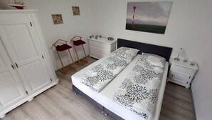 A bedroom with a bed, a nightstand, a dresser, a wardrobe, and a painting on the wall. - Vacation apartment WESER im Relax - Belum near Otterndorf LK Cuxhaven (Belum)