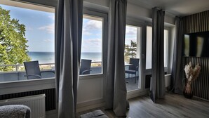 A room with large windows, a view of the sea, and a seating area with chairs. - Strandkoje 203 - Holiday apartment Scharbeutz directly on the beach - Strandkoje 203 for (Scharbeutz)
