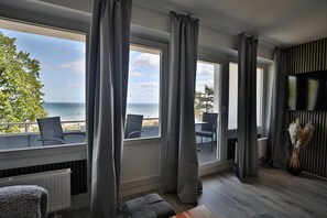 A room with large windows, a view of the sea, and a seating area with chairs. - Strandkoje 203 - Holiday apartment Scharbeutz directly on the beach - Strandkoje 203 for (Scharbeutz)
