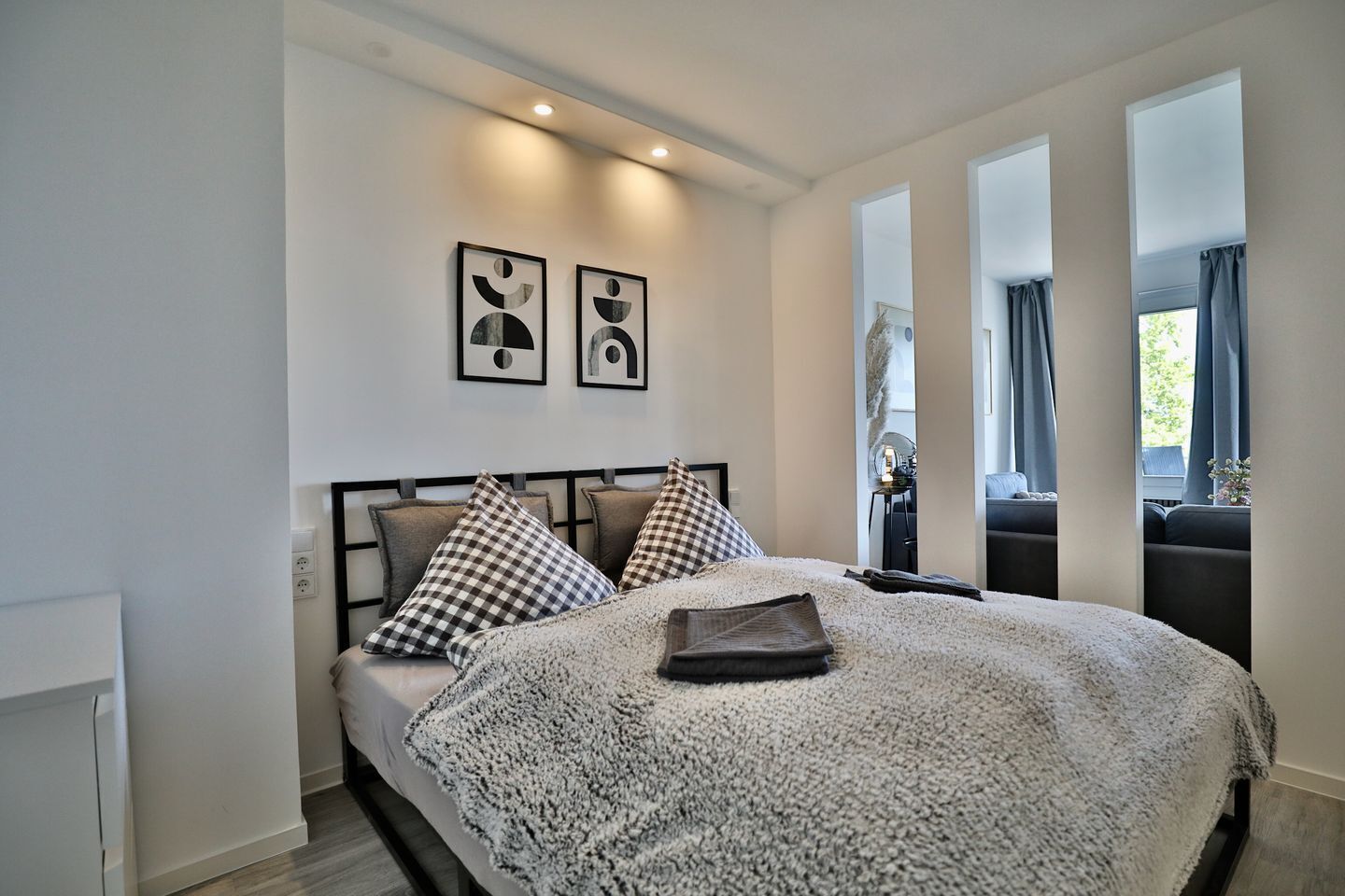 A bedroom with a bed, two pillows, a blanket, and two framed pictures on the wall.