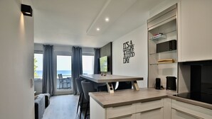 A modern kitchen with a dining area, a view to the outside, and a wall with a motivational quote. - Strandkoje 203 - Holiday apartment Scharbeutz directly on the beach - Strandkoje 203 for (Scharbeutz)