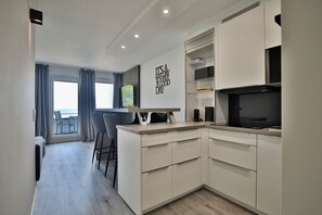 A modern kitchen with a dining area, a view to the outside, and a wall with a motivational quote. - Strandkoje 203 - Holiday apartment Scharbeutz directly on the beach - Strandkoje 203 for (Scharbeutz)