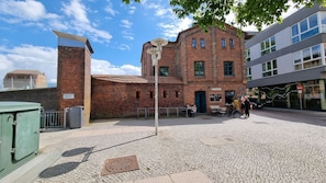 A brick building with a clock tower, outdoor seating, and a cobblestone plaza. - Fewo 1 im Alten Zollhaus Stralsund - Holiday apartment 1 in the old customs house directly at the (Stralsund)