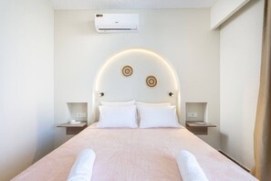 Ett hotellrum med en säng, två sängbord, en luftkonditioneringsanläggning och en väggmonterad lampa.