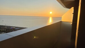 Een balkon met uitzicht op de ondergaande zon boven de zee.