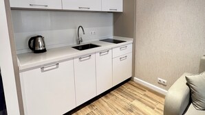 Een moderne keuken met witte kastjes, een spoelbak en een waterkoker.