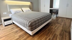 Een moderne slaapkamer met een bed, nachtkastjes, een bureau en een kledingkast.