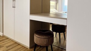 Een moderne slaapkamer met een grote kast, een spiegel, een bed en een klein krukje.