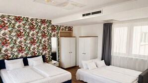 Quarto de hotel com duas camas, um guarda-roupa, um espelho e uma janela com cortinas.
