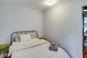 Une chambre à coucher avec un lit, une table de chevet verte et une porte donnant sur une salle de bain.