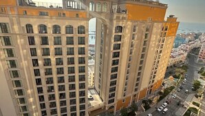 A high-rise building with multiple floors, a central courtyard, and a pool. - Dido Carthage Apartment (An Thoi)