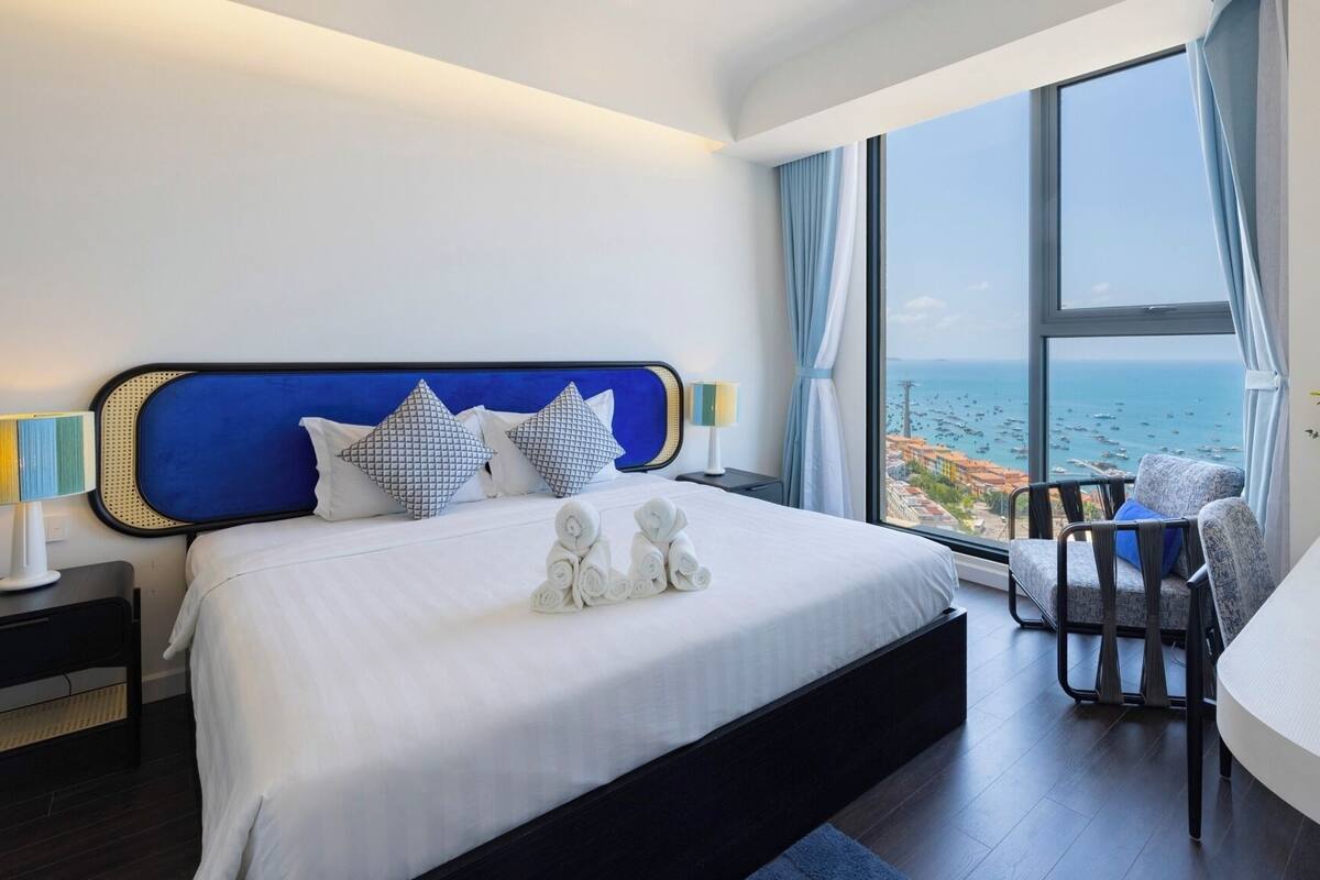 Habitación de hotel moderna con una cama grande, vista al mar y un área de descanso con vistas.