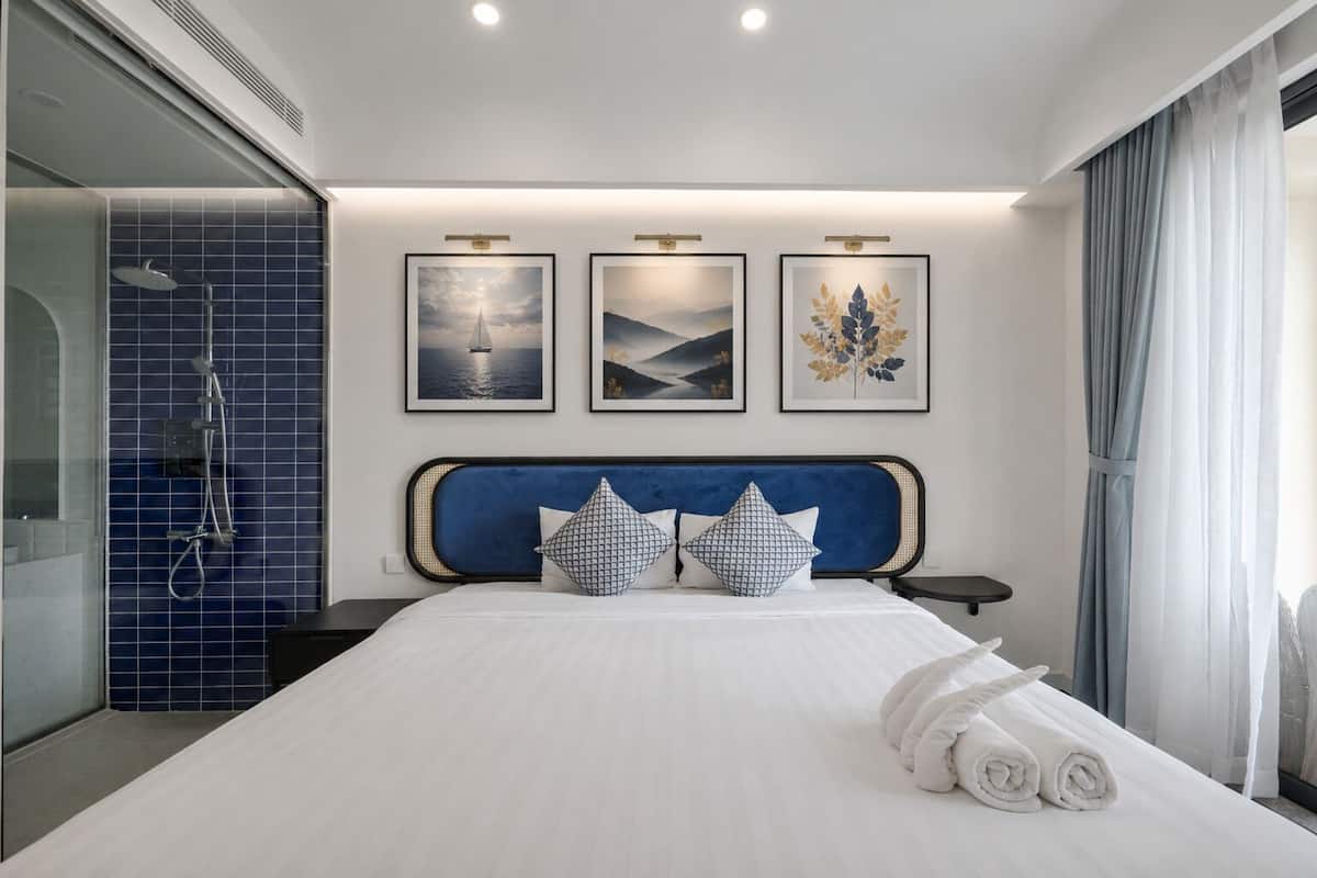 Un hotel moderno con una cama grande, zona de ducha y tres cuadros enmarcados en la pared.