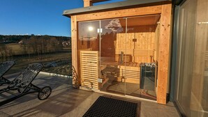 Een houten chalet met een glazen deur, buiten zitplaatsen en uitzicht op het landschap.