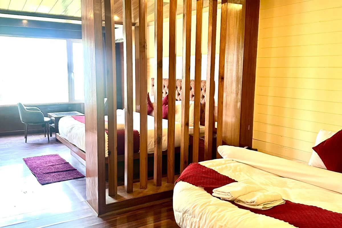 A bedroom with a wooden bed, a view of the outdoors, and a separate seating area with a table and chairs.