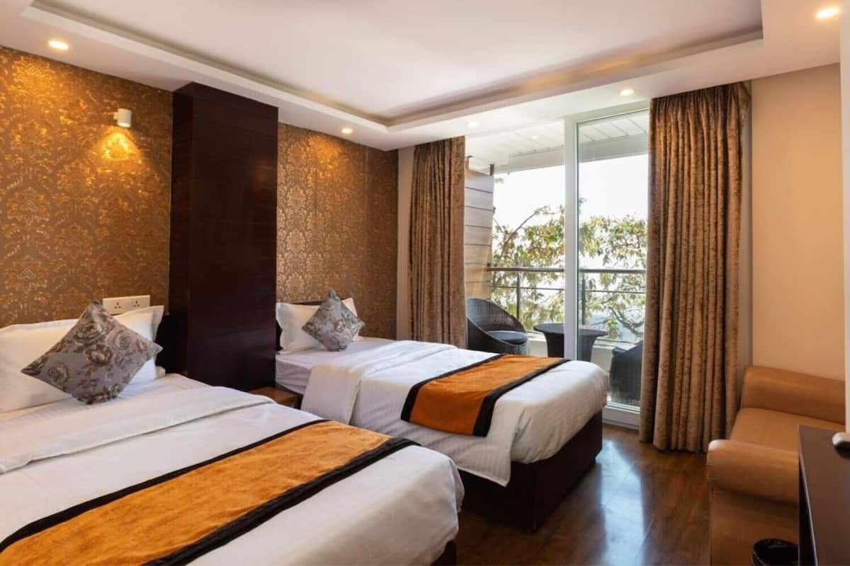 A hotel room with two beds, a balcony with a view, and a seating area.
