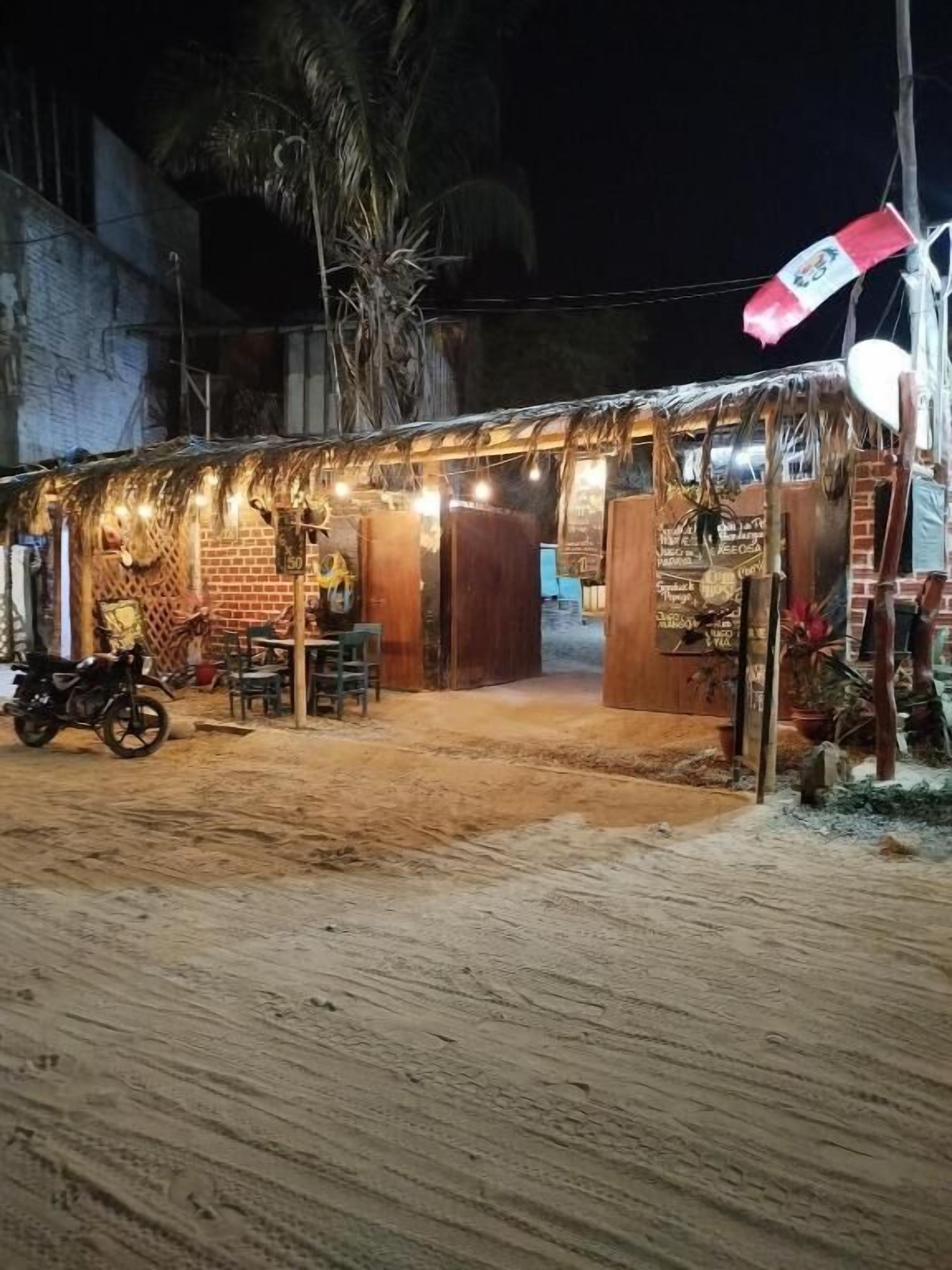 Un edificio rústico con techo de paja, puertas de madera y una motocicleta estacionada afuera.