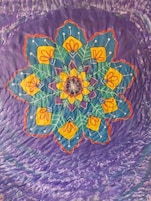 Un patrón de mandala colorido sobre un fondo púrpura texturizado.