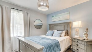 Une chambre à coucher avec un lit, une table de chevet, une lampe et un tableau au mur.
