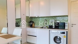 Una cucina moderna con mobili bianchi, una lavatrice, un forno a microonde e un lavello.