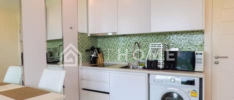 Una cocina moderna con armarios blancos, lavadora, microondas y fregadero.