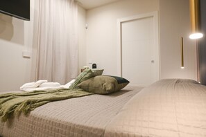A bedroom with a bed, a bedside table, a lamp, a door, and a curtain. - AURA Room- Aurisea Luxury Stays (Bari)