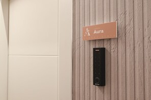 Segno a parete con il nome 'Aura' e un dispositivo nero sottostante.