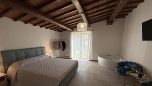 Un dormitorio con cama, bañera, una silla y una mesa.