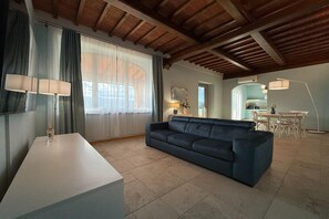 A living room with a sofa, a table, and a lamp. There is a kitchen area visible through an archway. - Spacious apartment in Poppi with shared pool (Poppi)