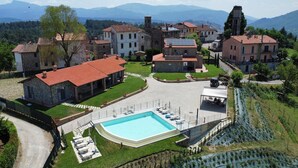 Una villa con piscina, rodeada de jardines exuberantes y un viñedo.