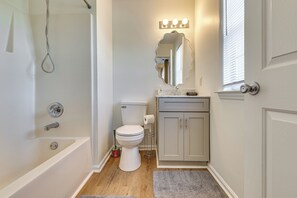 Ein Badezimmer mit Badewanne, Toilette, Waschtisch und einem beleuchteten Spiegel.