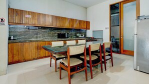A modern kitchen with wooden cabinets, a marble countertop, and a dining area with wooden chairs. - Modern Deluxe Double in Cirebon (Cirebon)