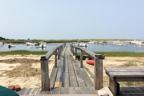 A wooden pier leading to a calm water body with boats docked. - Waterfront Studio w/ Dock & Beach Access in Truro! (Truro)