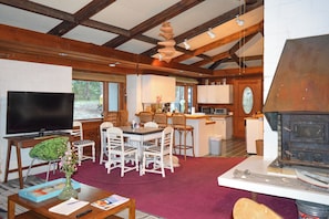 A living room with a television, dining area, kitchen, and fireplace.