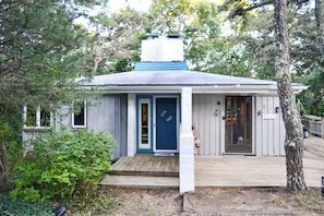 A small wooden cabin with a blue door, a small porch, and a dog standing by the door. - 2 Mi to Beaches: Cape Cod Cottage w/ Fire Pit (Truro)