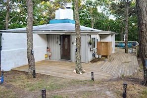 A small, single-story building with a deck, surrounded by trees. - 2 Mi to Beaches: Cape Cod Cottage w/ Fire Pit (Truro)