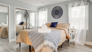 A bedroom with a bed, a bedside table, a mirror, and a wall art piece. - Kayaks, Paddleboat! Lakefront Retreat in Barnstead (Barnstead)