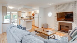 A modern living room with a grey sofa, a wooden coffee table, and a fireplace. - Kayaks, Paddleboat! Lakefront Retreat in Barnstead (Barnstead)