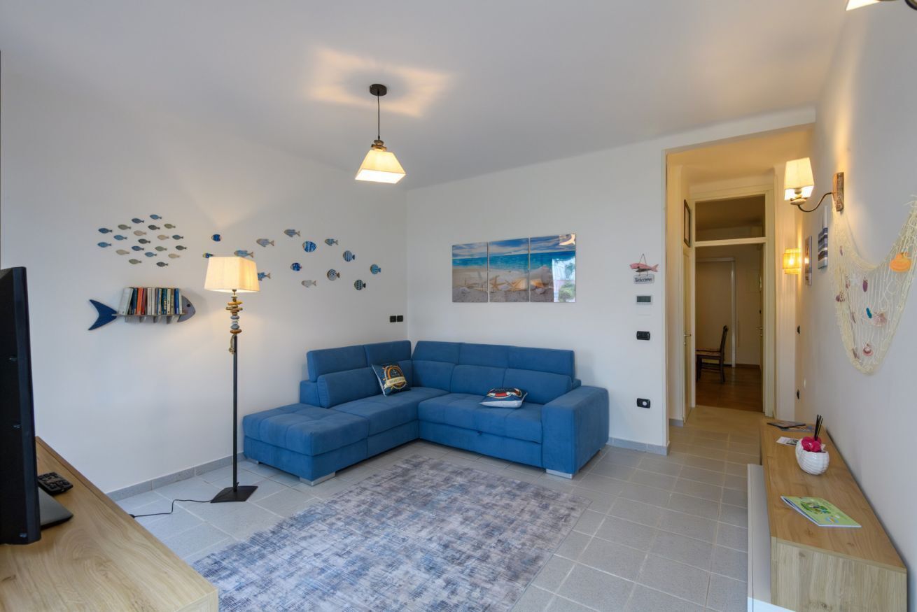 A living room with a blue sofa, a floor lamp, a rug, a TV, and a wall with fish decals.