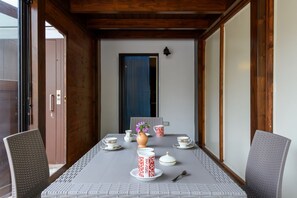Ein Esstisch mit Geschirr in Weiß und Rot, einer Blumenvase und einem blauen Vorhang im Hintergrund.
