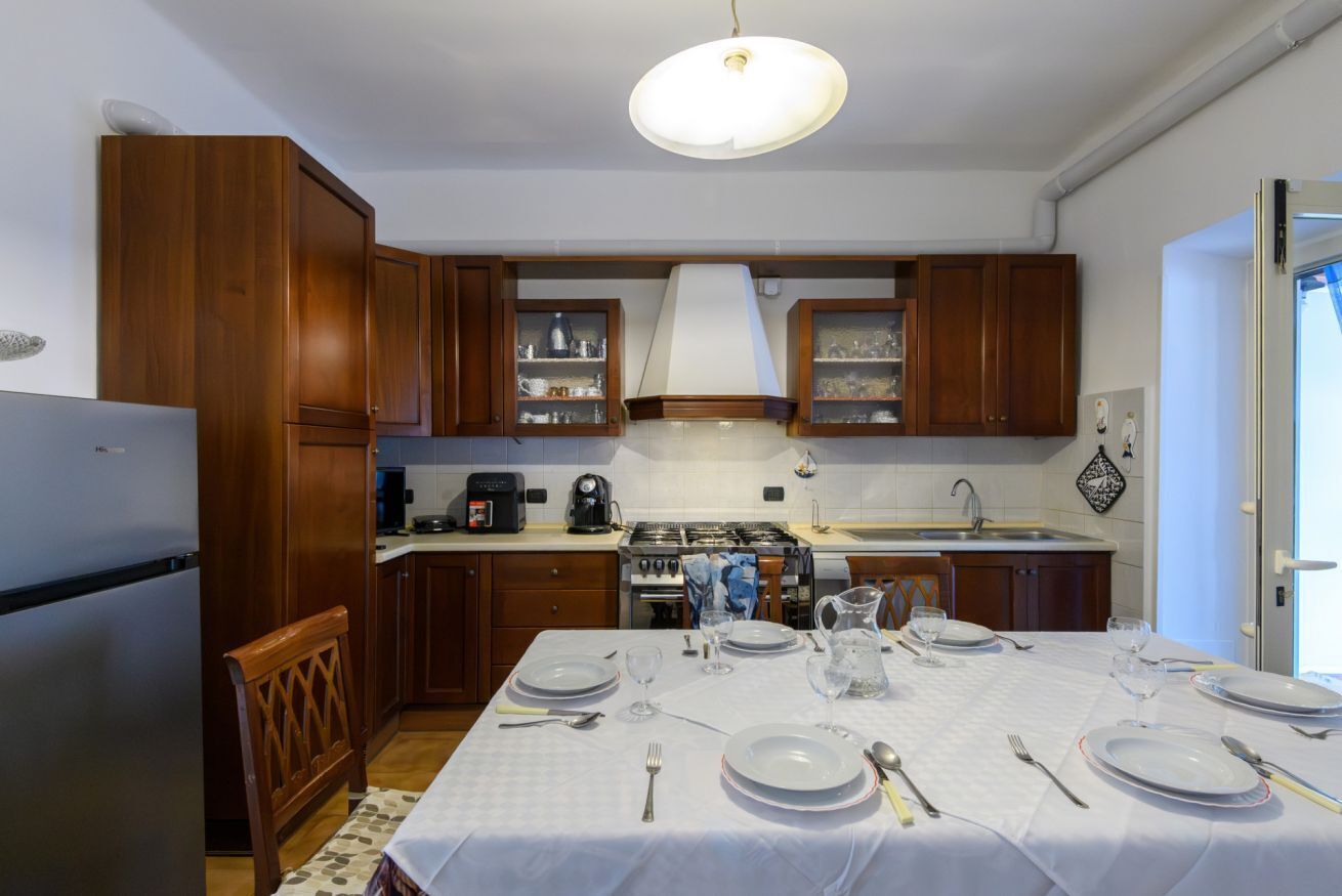 Une cuisine avec des meubles de rangement en bois, une cuisinière, un évier et une table à manger pour quatre personnes.