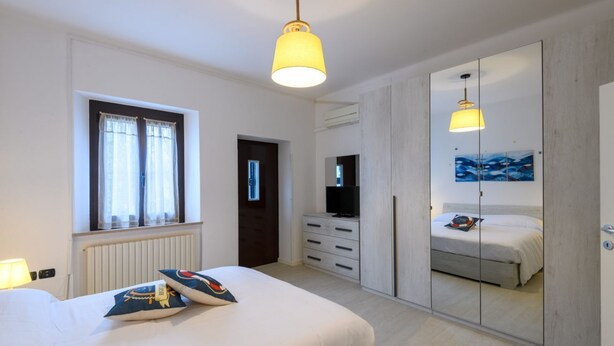 Un dormitorio con cama, cómoda, televisión, espejo y ventana.