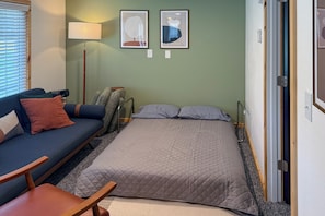 Un dormitorio con una cama, un sofá, una silla y dos lámparas fijadas a la pared.