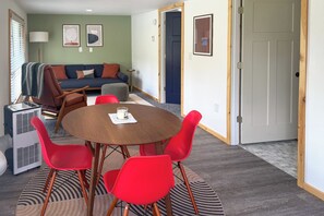 Ein Wohnzimmer mit einer Couch, einem Esstisch und Stühlen sowie einer Tür.
