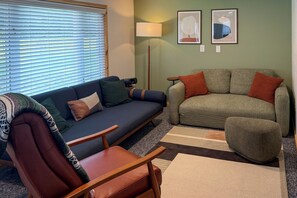 Ein Wohnzimmer mit Sofa, Sessel und einem kleinen Tisch mit Lampe.