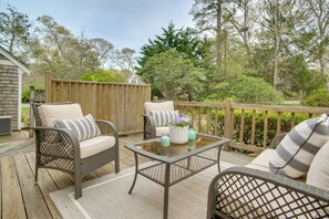Eine Terrasse im Freien mit Korbmöbeln, einem Tisch mit Glasplatte und einem Holzzaun.