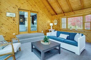 Ein Holzinnenraum mit einer Couch, einem Couchtisch und einer Treppe, die zu einem Balkon führt.